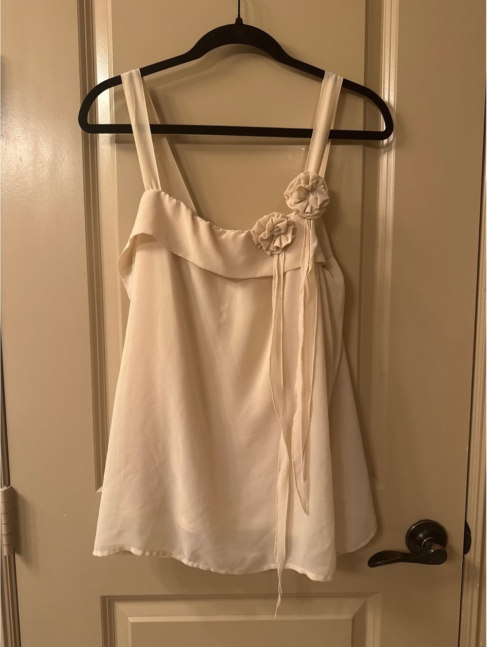 Elegant Cream Sleeveless Top with Floral Accent and Ruffle Detail